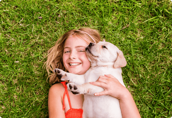 Girl laying on the grass holding a puppy